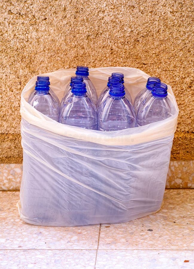 Empty Plastic Bottles in Plastic Bag Near Stone Wall Stock Image