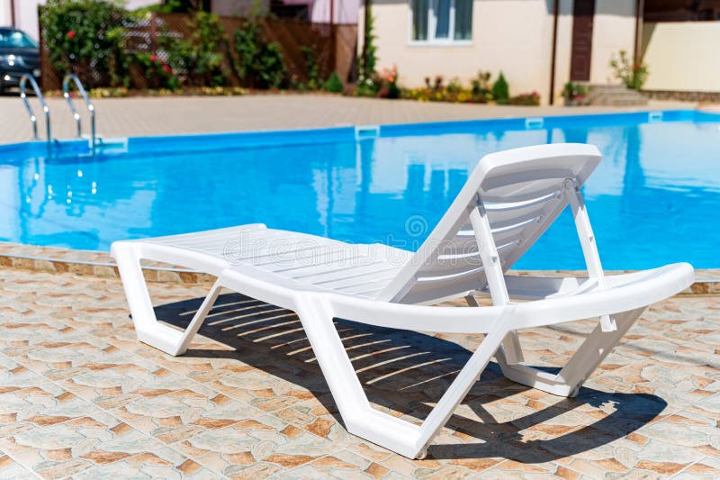 Empty Plastic White Deck Chairs Near the Swimming Pool Stock Photo