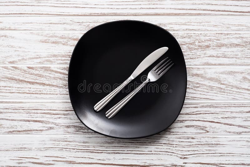 Empty plate fork knife silverware white wooden table background stock photography