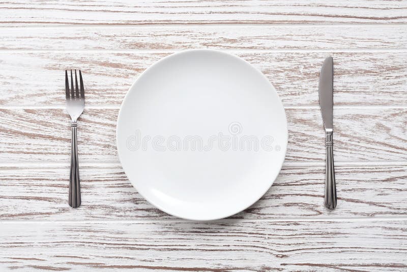 Empty plate fork knife silverware white wooden table background stock photos