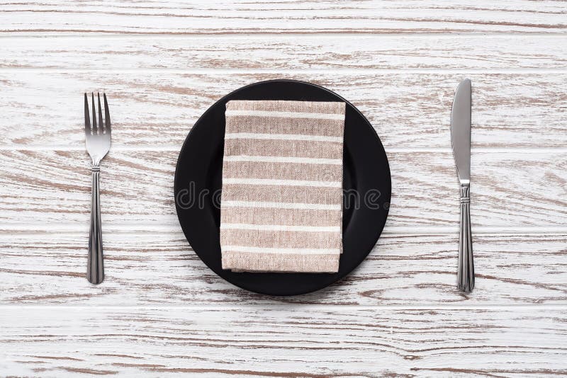 Empty plate napkin fork knife silverware white wooden table back royalty free stock photography