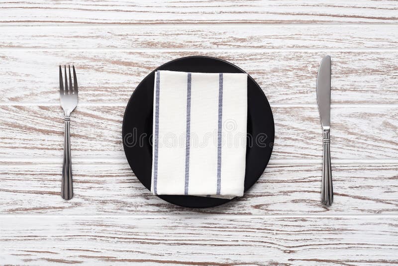 Empty plate napkin fork knife silverware white wooden table back royalty free stock images