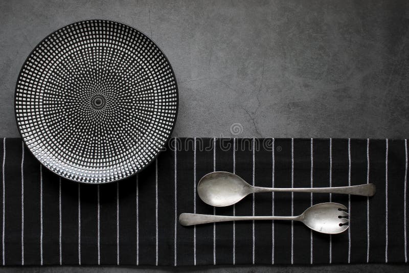 Empty plate with silver cutlery on the black background, close up. Restaurant menu concept, template design. Top view. Copy space