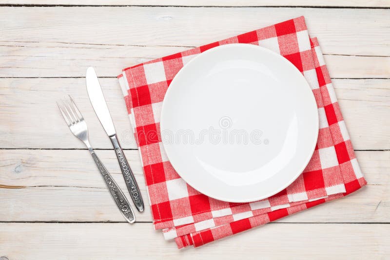 Empty plate, silverware and towel over wooden table background royalty free stock photo