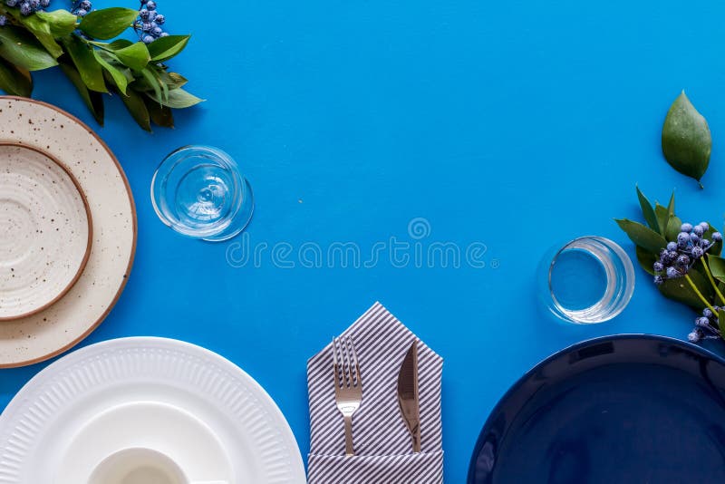 Empty plates and flowers frame for table setting on blue background top view copyspace. Empty plates, tableware and flowers frame for table setting on blue royalty free stock image Empty plates and flowers frame for table setting on blue background top view copyspace. Empty plates, tableware and flowers frame for table setting on blue royalty free stock image