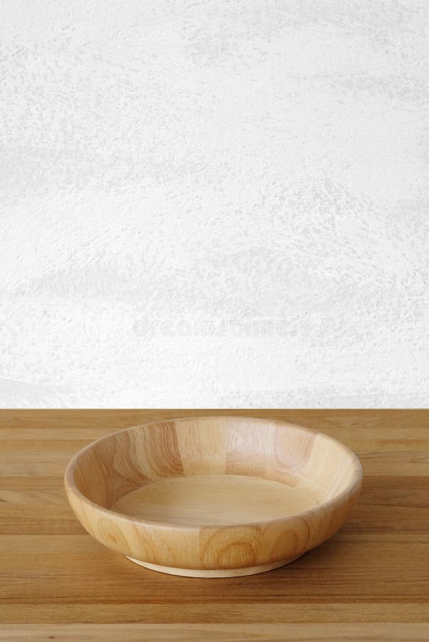 Empty round wooden plate on wood table and cement wall backgroun stock image