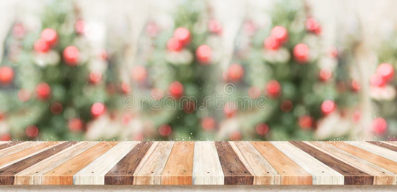 Empty rustic wood plank table top with abstract blur christmas tree red decor ball and snow fall background with bokeh light,winter Holiday backdrop,Mock up banner for display of product or promotion