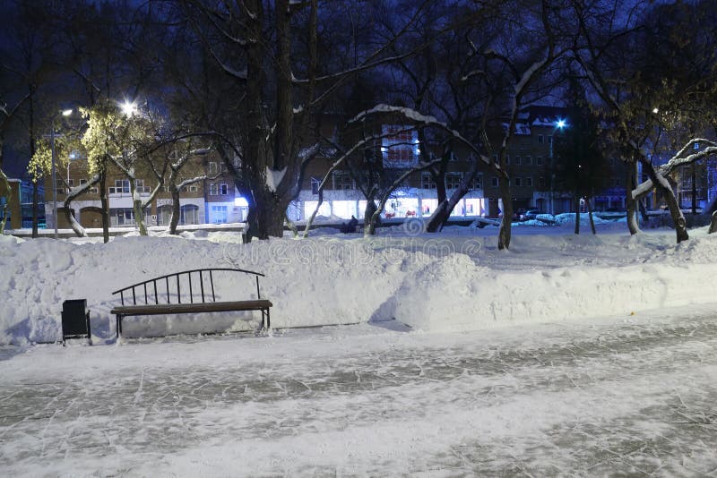 Empty stone causeway, bench and white snow in park at winter