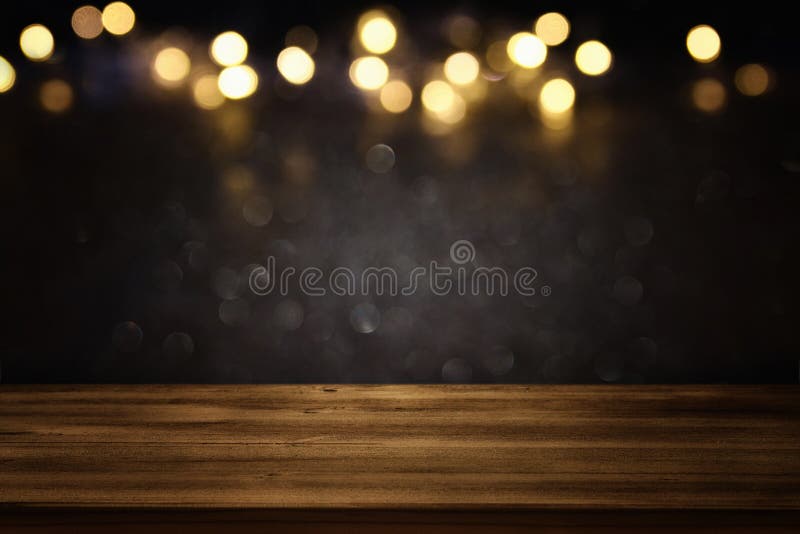 Empty table in front of black and gold glitter lights background