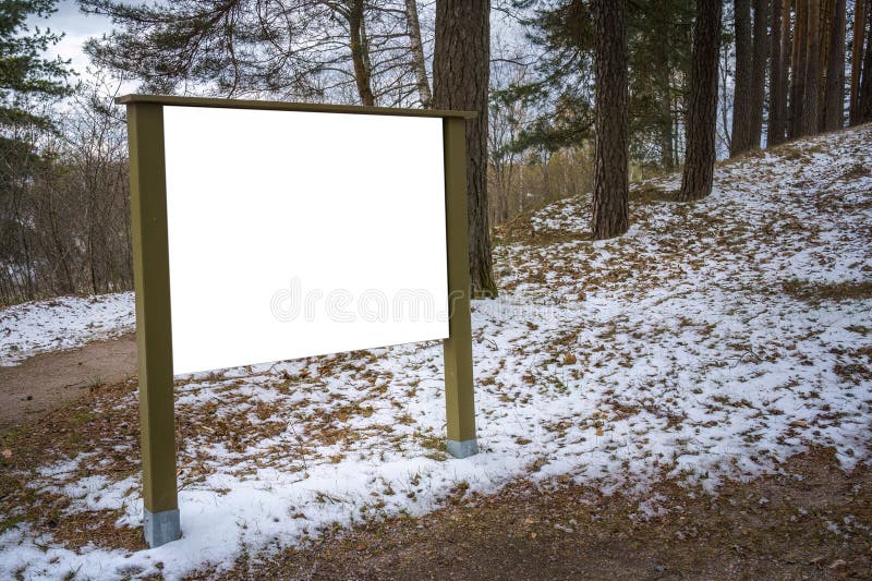 Empty white billboard in the park with patches of snow royalty free stock photo