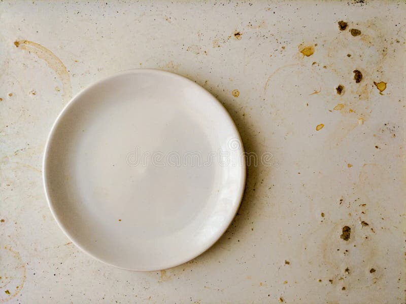 Empty white plate on dirty stained board. Attrition concept.