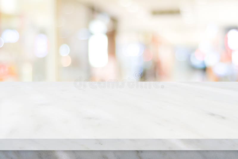 Empty white table top, counter, desk over blur perspective store with bokeh light background, White marble stone table, shelf and. Blurred shop for food