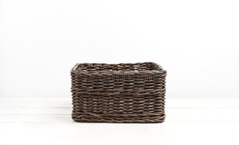 Empty wicker brown rattan basket on a white wooden background and white wall. Natural eco handmade item for home