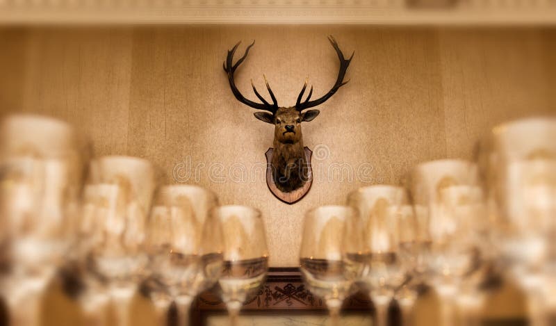 Empty wine glasses with a deer head trophy on the wall