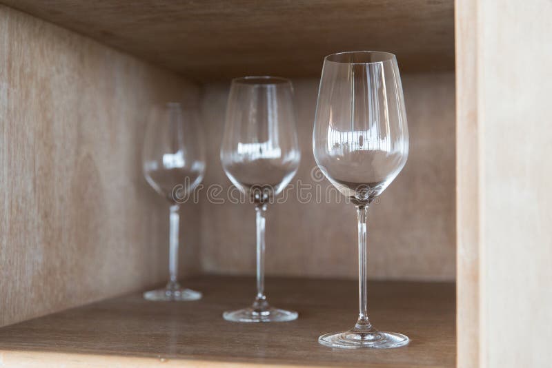 Winery, glassware and alcohol concept - empty wine glasses set on shelf at restaurant