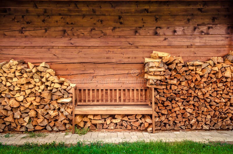 Empty wooden bench with pile of firewood