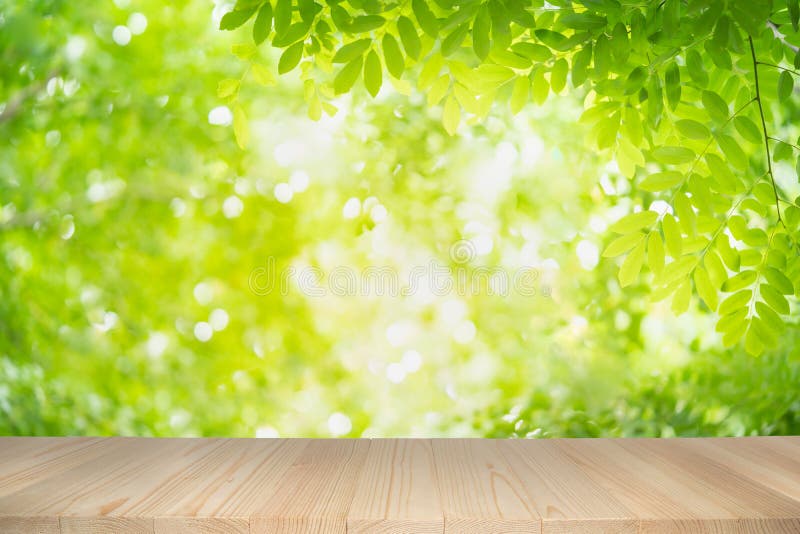 Empty wooden table on green nature background with beauty bokeh under sunlight