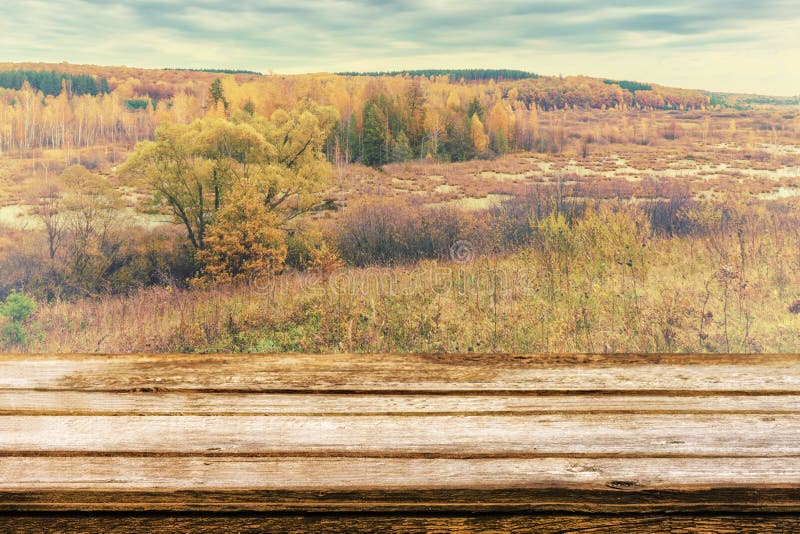 Empty wooden table with picturesque autumn landscape of view from the hill to the lowland with forest and swamps. Mock up for stock images Empty wooden table with picturesque autumn landscape of view from the hill to the lowland with forest and swamps. Mock up for stock images