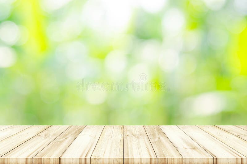 Empty wooden table top with blurred green natural background.