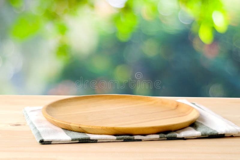 Empty wooden tray on table over blur green park background, food