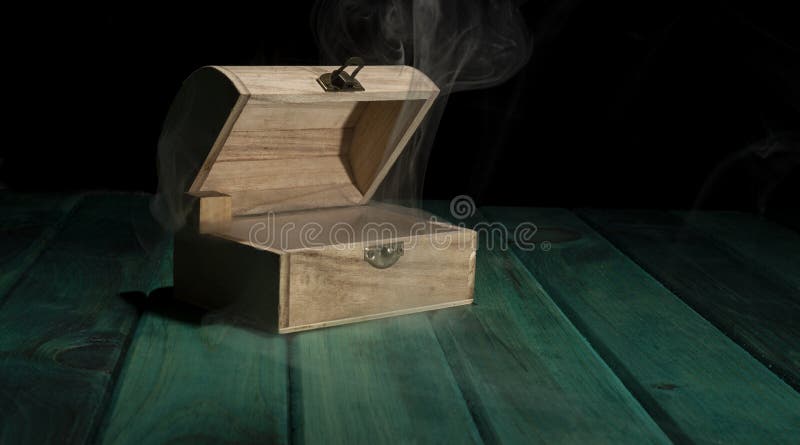 Empty wooden treasure box on green table with smoke all around