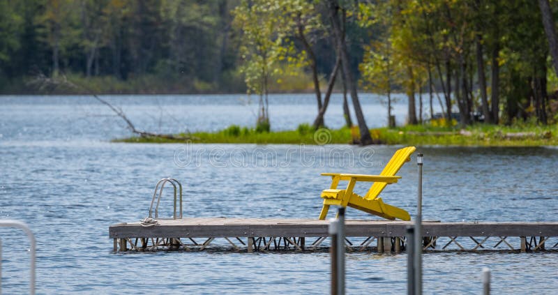 Empty yellow deck chair on a dock on the lake. royalty free stock photos