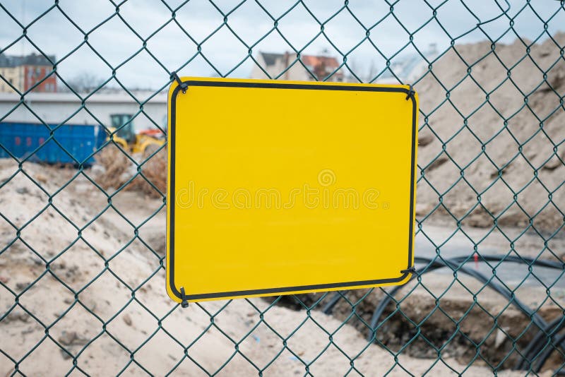 Empty yellow sign on construction site fence - warning sign mock-up royalty free stock image