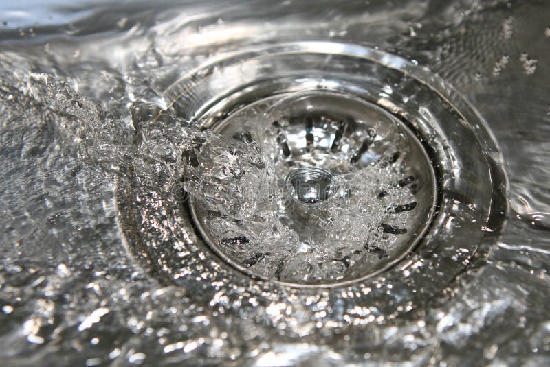 En bas du drain. Plan rapproché d'eau propre fonctionnant en bas du trou de fiche d'un bassin d'acier inoxydable