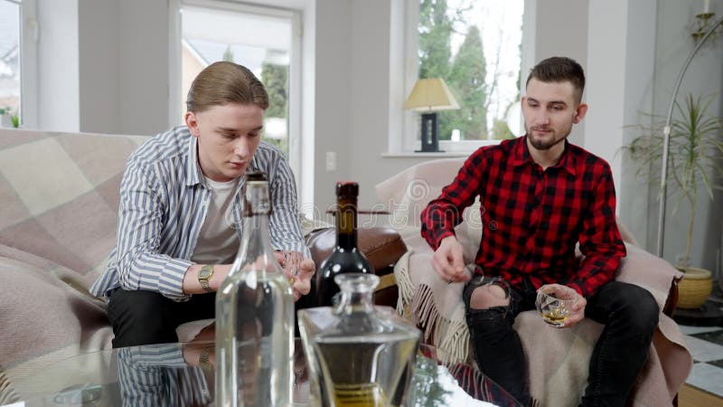 En bild av en desperat ung man som klagar över problem för en vän. Två stiliga kaukasiska vänner dricker alkohol och lager videofilmer