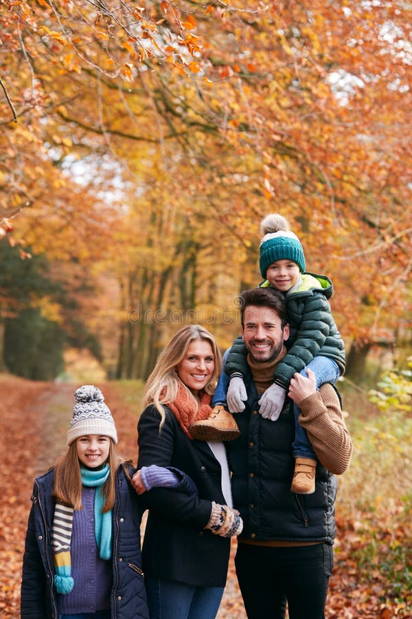 En bild av familjen som går längs höstskogar med far som bär på skuldra royaltyfria foton