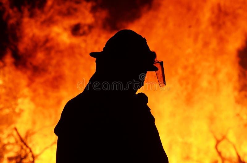 A black silhouette image of a single brave fireman standing in front and keep control of a blazing hot Australian bushfire. He is watching that the leaping flames do not catch any surrounding grass or trees which would prove to cause a disaster in the area and a threat to surrounding homes. Photograph taken in small outback Queensland country village called Kalbar on the Scenic Rim, Australia. A black silhouette image of a single brave fireman standing in front and keep control of a blazing hot Australian bushfire. He is watching that the leaping flames do not catch any surrounding grass or trees which would prove to cause a disaster in the area and a threat to surrounding homes. Photograph taken in small outback Queensland country village called Kalbar on the Scenic Rim, Australia.