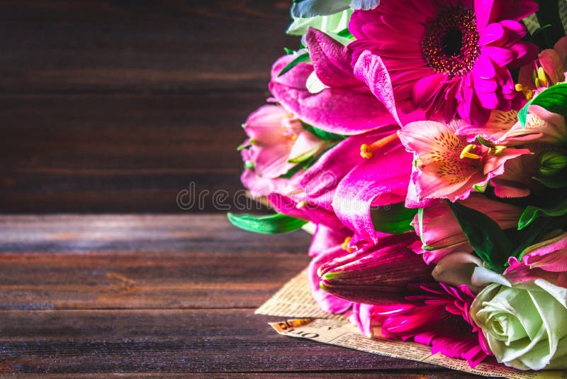 En bukett av blommor från lilja, gerbera, vita rosor och alstroemeria på en brun trätabell En ferie en gåva arkivbild En bukett av blommor från lilja, gerbera, vita rosor och alstroemeria på en brun trätabell En ferie en gåva arkivbild