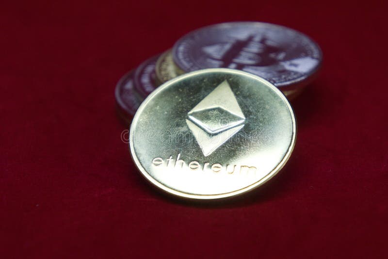 En bunt av guld- och silvercryptocurrencymynt med ethereum framtill på en röd sammetbakgrund royaltyfri foto En bunt av guld- och silvercryptocurrencymynt med ethereum framtill på en röd sammetbakgrund royaltyfri foto