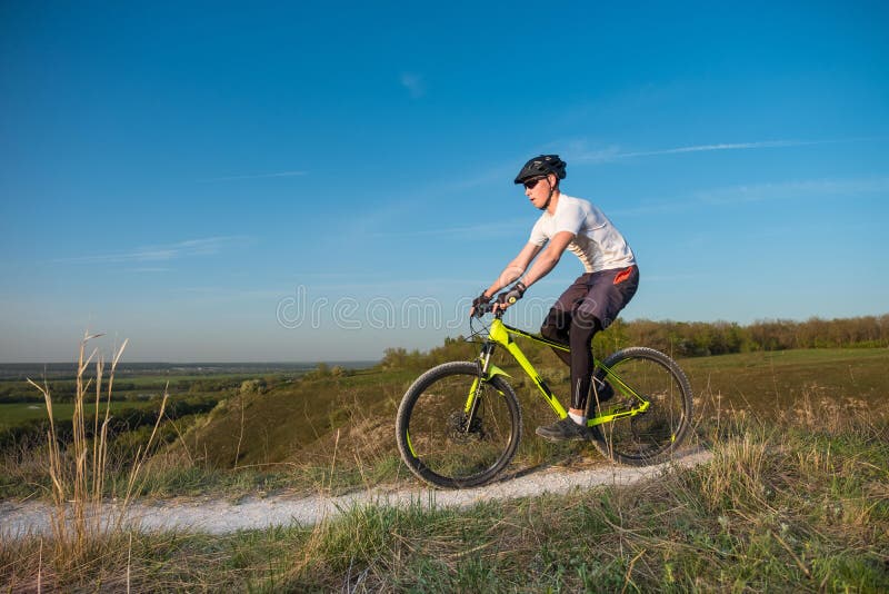 En cyklist i en orange hoodie rider en cykel längs en bergbana Begreppet av extrema sportar royaltyfria bilder En cyklist i en orange hoodie rider en cykel längs en bergbana Begreppet av extrema sportar royaltyfria bilder