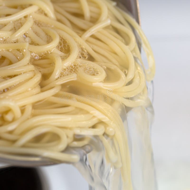 En faisant cuire le repas de nouilles de spaghetti filtrez les pâtes de l'eau chaude image libre de droits En faisant cuire le repas de nouilles de spaghetti filtrez les pâtes de l'eau chaude image libre de droits