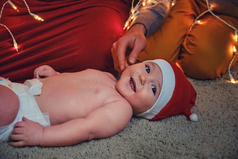 En familj med nyfödd i julgranen på kvällens vardagsrum på kvällen. royaltyfri bild