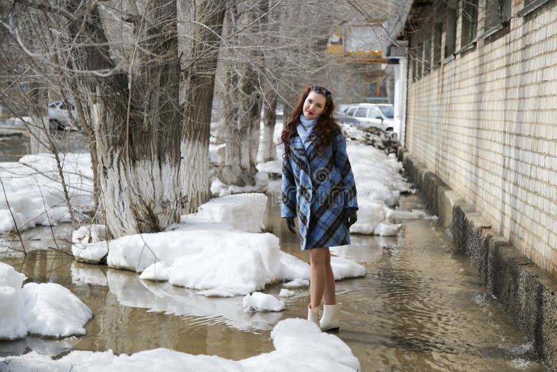 En flicka går på våren på snö och vatten arkivfoton