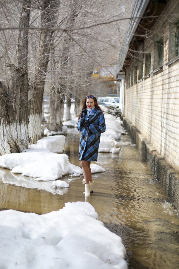 En flicka går på våren på snö och vatten fotografering för bildbyråer