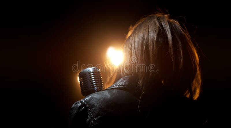 En flicka i ett läderomslag med en mikrofon i ljuset