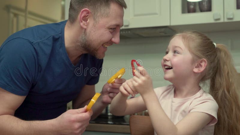 En flicka och hennes pappa leker med grönsaker som gör mat rolig arkivfilmer