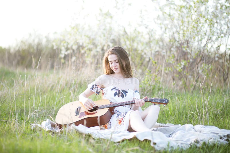 En flicka på gröngräs spelar gitarr arkivfoton
