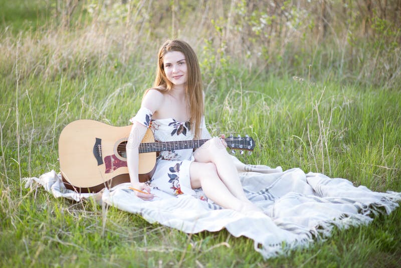 En flicka på gröngräs spelar gitarr royaltyfria bilder