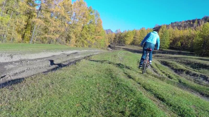 En flicka rider en cykel längs en skogväg