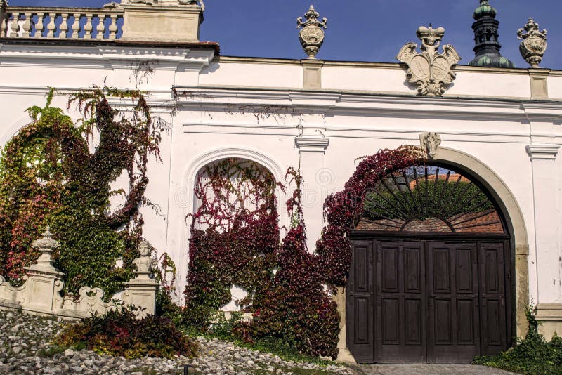En forntida vägg med träportar som täckas med den färgrika murgrönan runt om chateauen royaltyfri fotografi En forntida vägg med träportar som täckas med den färgrika murgrönan runt om chateauen royaltyfri fotografi