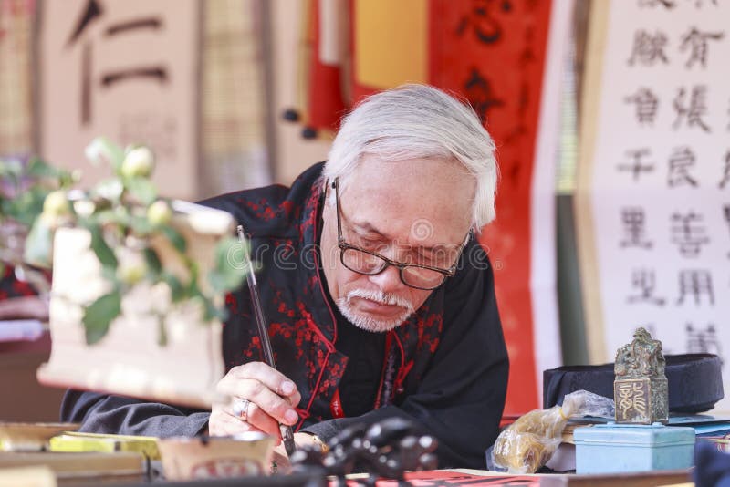 En forskare skriver kinesiska kalligrafitecken på templet av litteratur arkivfoton En forskare skriver kinesiska kalligrafitecken på templet av litteratur arkivfoton