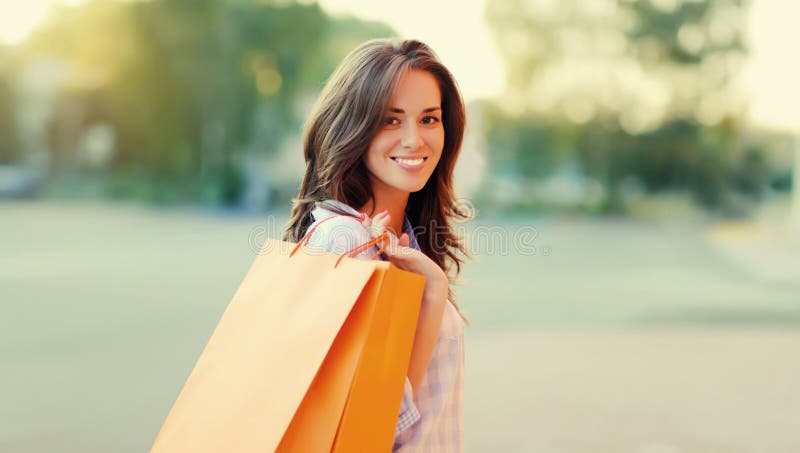 En glad brunette-ung kvinna med shoppingväskor som går i stan fotografering för bildbyråer