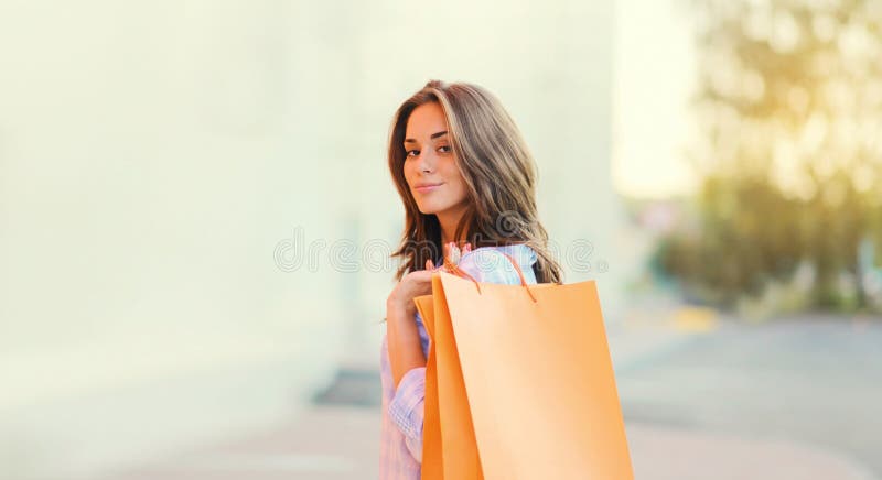 En glad brunette-ung kvinna med shoppingväskor som går i stan royaltyfria bilder