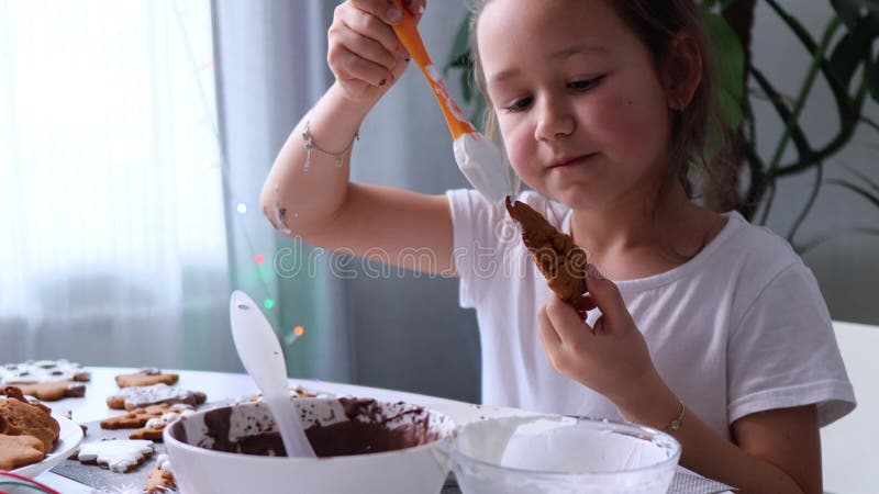 En glad flicka förbereder sig för semester och målar kakor med isbildning