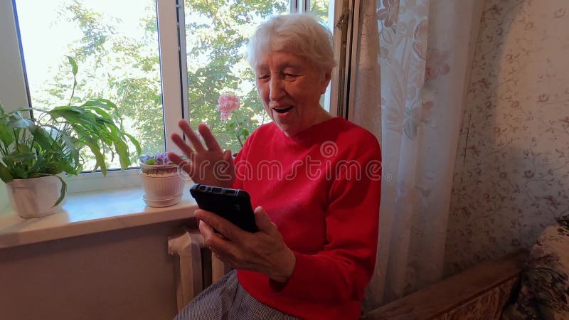 En glad medelålders modig kvinna som håller på med smarta telefoner och tittar på mobiltelefonskärmen med sociala medier arkivfilmer