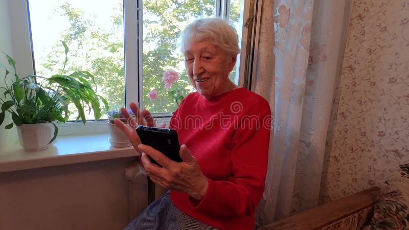 En glad medelålders modig kvinna som håller på med smarta telefoner och tittar på mobiltelefonskärmen med sociala medier stock video